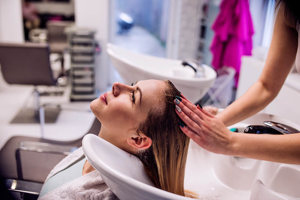 Hairstylist washing woman's hair